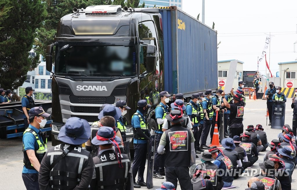 This photo taken on June 13, 2022 shows members of the cargo truckers' union staging a rally against a cargo truck delivering products at the Inland Container Deport (ICD) in Uiwang, Gyeonggi Province, demanding higher pay as fuel prices surge. (Yonhap)