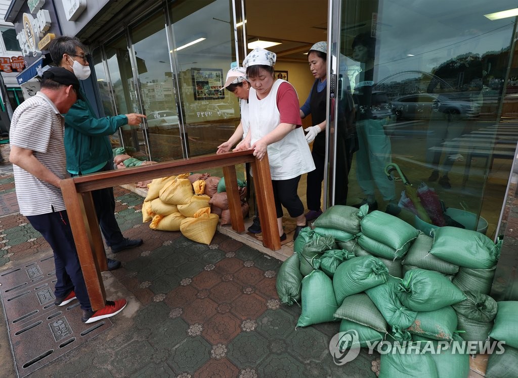Workers at a restaurant in Tongyeong, South Gyeongsang Province, move a table on Sept. 5, 2022, to prepare for the approach of the super strong Typhoon Hinnamnor toward the Korean Peninsula. (Yonhap)