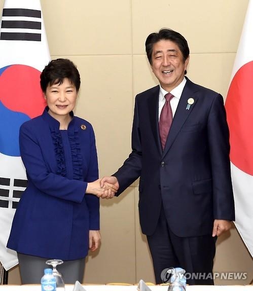 President Park Geun-hye (L) shakes hands with Japanese Prime Minister Shinzo Abe before their summit on the sidelines of multiple summits with the leaders of the Association of Southeast Asian Nations in the Laotian capital of Vientiane on Sept. 7, 2016. (Yonhap)