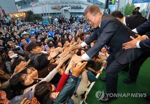 Presidential front-runner Moon Jae-in of the Democratic Party (R) shakes hands with his supporters while electioneering in Gwangju, located some 300 kilometers southwest of Seoul, on April 18, 2017. (Yonhap)