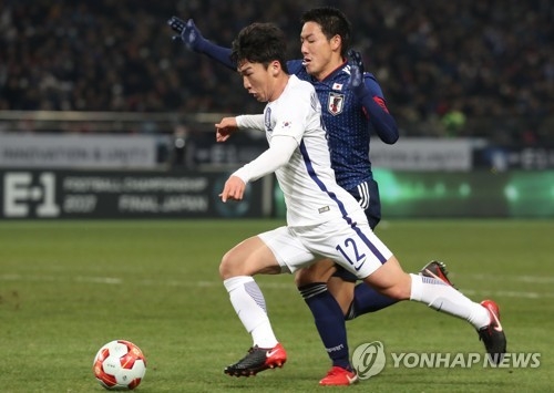 In this file photo taken on Dec. 16, 2017, South Korean defender Kim Min-woo (L in white) battles a Japanese player during their match at the East Asian Football Federation (EAFF) E-1 Football Championship at Ajinomoto Stadium in Tokyo. (Yonhap)