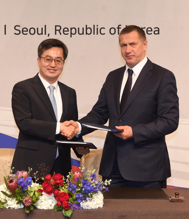 South Korean Finance Minister Kim Dong-yeon (L) shakes hands with his Russian counterpart, Yuri Trutnev, after signing the agreed-on minutes from the South Korea-Russia Joint Committee on Economic, Scientific and Technological Cooperation meeting in Seoul, on June 7, 2018. (Yonhap)