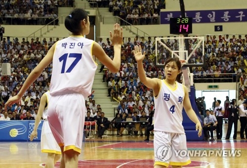 In this pool photo taken July 4, 2018, North Korea's Pak Jin-a (L) high-fives with South Korea's Shim Sung-young during a women's basketball mixed game between two Koreas at Ryugyong Chung Ju-yung Gymnasium in Pyongyang. (Yonhap)