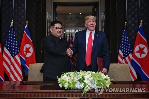 This file photo shows U.S. President Donald Trump (R) and North Korean leader Kim Jong-un shaking hands after signing a joint statement in Singapore on June 12, 2018. (Yonhap)