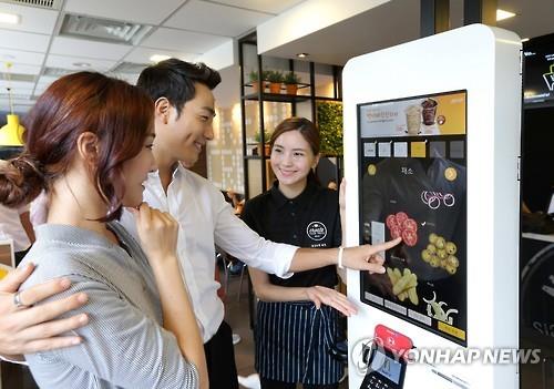 This undated photo provided by McDonald's shows customers ordering food using a kiosk. (Yonhap) 