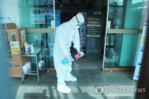 A hospital worker at a hospital in Cheongdo, 320 kilometers southeast of Seoul, disinfects an entrance way after many patients and workers were diagnosed with the novel coronavirus on Feb. 21, 2020. (Yonhap)