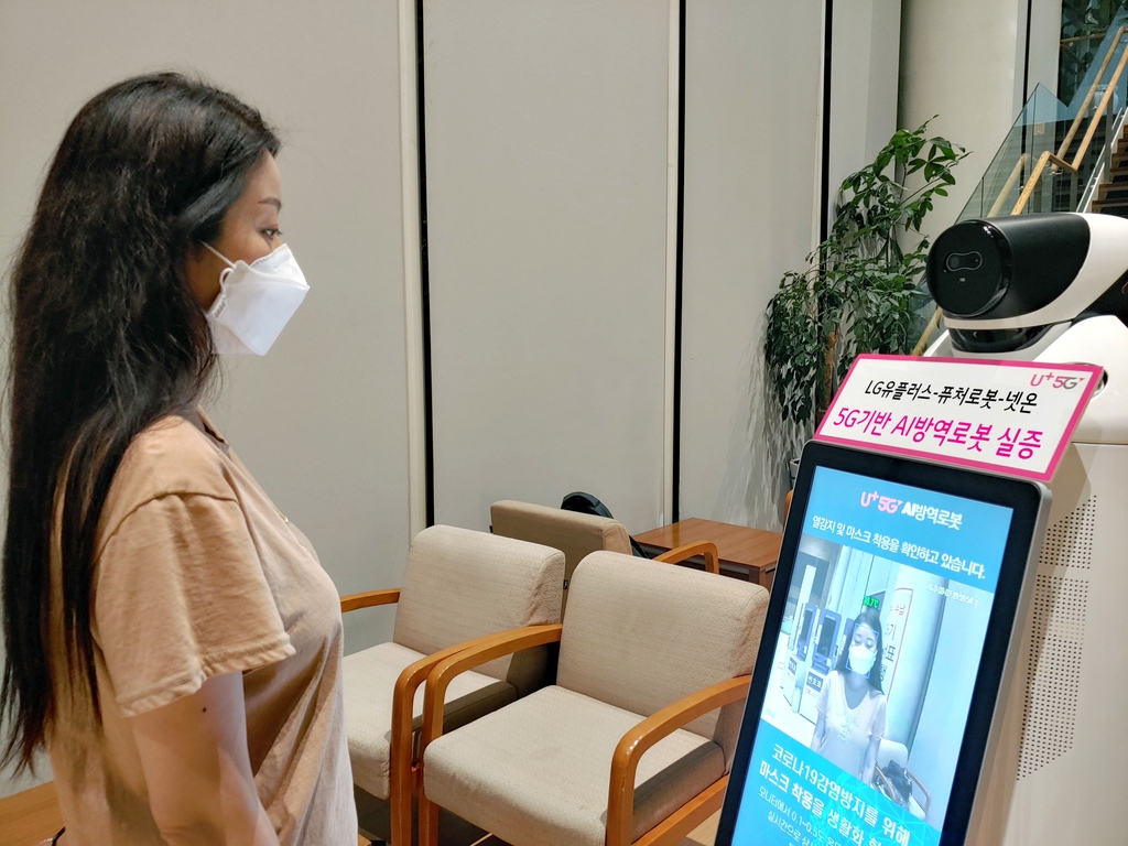 LG Uplus Corp.'s robot co-developed by robotics firm FutureRobot Co. and facial recognition technology developer Neton checks a model's temperature and whether she is properly wearing a mask in this photo provided by the company on Sept. 3, 2020. (PHOTO NOT FOR SALE) (Yonhap)