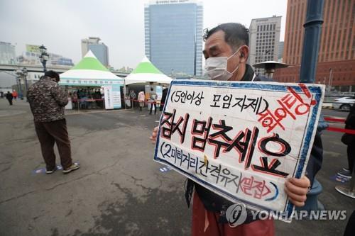 A citizen holds up a sign near Seoul Station on Feb. 11, 2021, calling for compliance with a government ban on gatherings of five or more people as the country celebrates the Lunar New Year. (Yonhap)