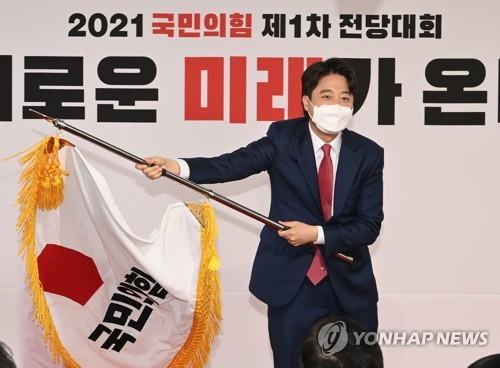 Lee Jun-seok waves the flag of the People Power Party after winning the party's chairmanship in a party convention on June 11, 2021. (Yonhap)