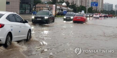 Cars travel on a flooded road in Gangneung, Gangwon Province, on Aug. 8, 2021. (Yonhap)