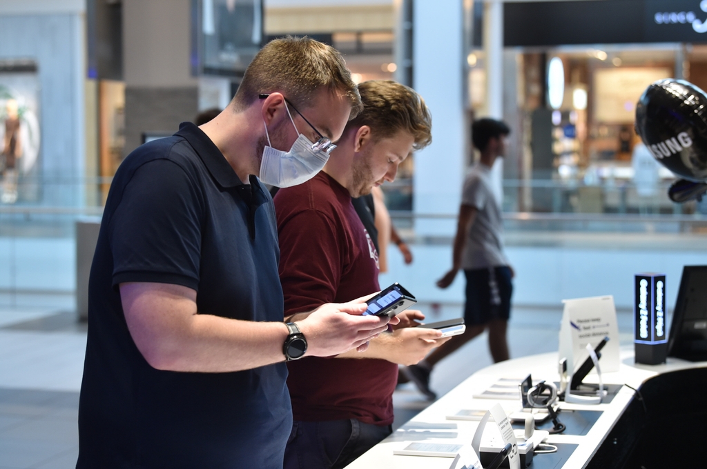 This photo provided by Samsung Electronics Co. on Aug. 27, 2021, shows American shoppers checking the company's Galaxy Z Fold3 and Galaxy Z Flip3 foldable smartphones at the Samsung Experience Store in Garden City, New York. (PHOTO NOT FOR SALE) (Yonhap)