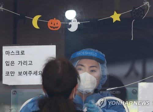 A medical worker takes a sample from a woman at a COVID-19 testing station with Halloween decorations in Seoul on Oct. 26, 2021. (Yonhap) 