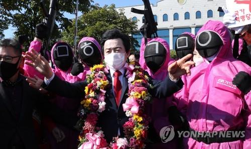 Huh Kyung-young is surrounded by people parodying notorious guards in the Netflix series "Squid Game" after he registered his preliminary presidential candidacy with the national election watchdog on Oct. 18, 2021. (Yonhap) 