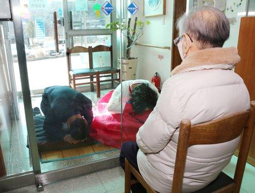 This photo taken on Jan. 31, 2022, and provided by Chilgok County shows people performing a formal Korean bow, called "sebae", to their mother at a nursing home in Chilgok, North Gyeongsang Province, with the glass door closed due to the spreading omicron variant. (PHOTO NOT FOR SALE) (Yonhap) 