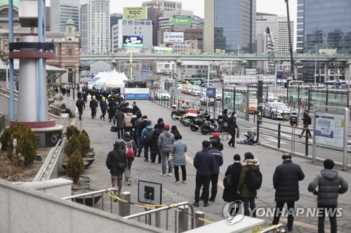 People wait in line to get tested for the coronavirus in front of a testing center at Seoul Station on March 8, 2022. (Yonhap)