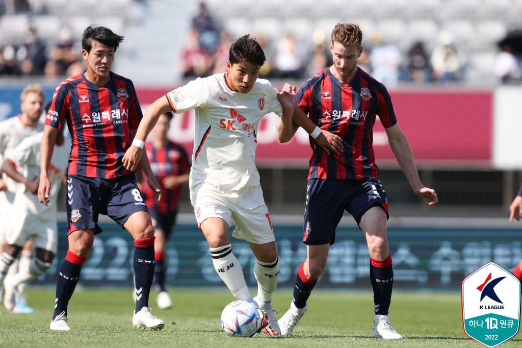 Joo Min-kyu of Jeju United (C) dribbles past Jeong Jae-yong (L) and Lachlan Jackson of Suwon FC during the clubs' K League 1 match at Suwon Stadium in Suwon, 45 kilometers south of Seoul, on May 15, 2022, in this photo provided by the Korea Professional Football League. (PHOTO NOT FOR SALE) (Yonhap)