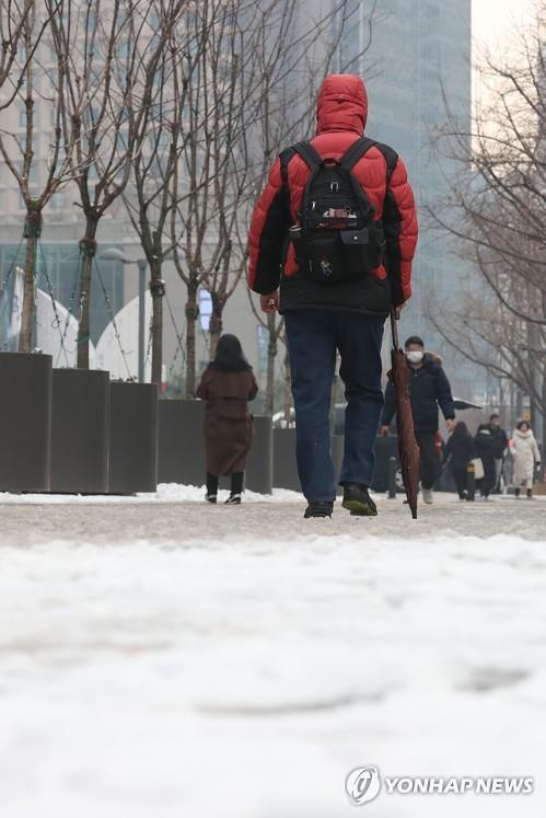 A pedestrian walks on a sidewalk covered in snow in Seoul on Dec. 21, 2022. (Yonhap)