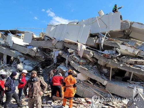 Members of South Korea's disaster relief team dispatched to Turkey search for survivors, with the help of a bandaged rescue dog, at the site of a collapsed building in Antakya, southeastern Turkey, in this photo provided by the team on Feb. 11, 2023. (Yonhap)