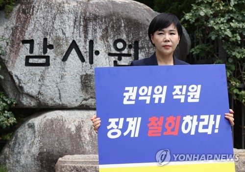 Jeon Hyun-heui, chairperson of the Anti-Corruption and Civil Rights Commission (ACRC), holds a placard demanding the Board of Audit and Inspection (BAI) withdraw its disciplinary action against an ACRC worker, in front of the BAI's building in Seoul, on June 9, 2023. (Yonhap)