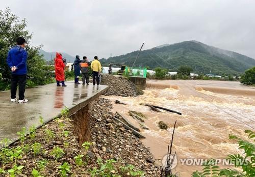 Los funcionarios inspeccionan el sitio de un terraplén derrumbado cerca de un arroyo después de las fuertes lluvias en el condado central de Cheongyang el 15 de julio de 2023. (Yonhap)