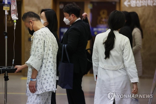 A patient and a doctor move about a hospital in Seoul on Feb. 27, 2024. (Yonhap)