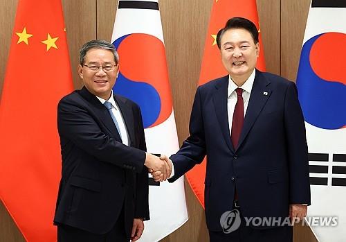 El presidente Yoon Suk Yeol (derecha) y el primer ministro chino Li Qiang posan para una fotografía durante su reunión en la oficina presidencial en Seúl, el 26 de mayo de 2024. (Yonhap)