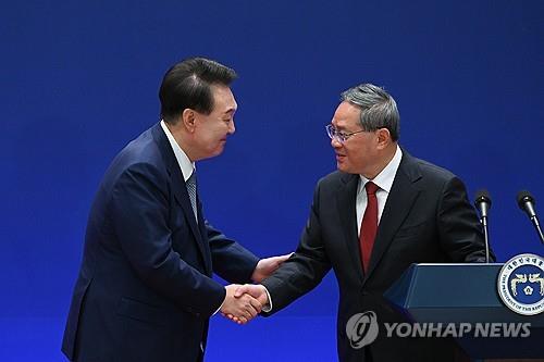 President Yoon Suk Yeol (L) shakes hands with Chinese Premier Li Qiang after holding a joint press conference with Japanese Prime Minister Fumio Kishida following their trilateral summit in Seoul on May 27, 2024, in this photo provided by Yoon's office. (PHOTO NOT FOR SALE) (Yonhap) 