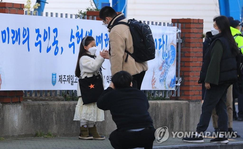 Un candidat est encouragé par sa petite sœur devant un centre d'examen au lycée Jeil sur l'île de Jeju, le jeudi 3 décembre 2020. 