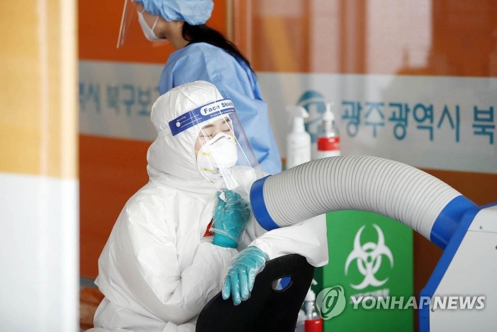 Une membre du personnel médical se rafraîchit devant un climatiseur dans un centre de dépistage du nouveau coronavirus (Covid-19) à Gwangju, à 330 km au sud de Séoul, le lundi 31 mai 2021. (Photo fournie par la mairie de l'arrondissement Buk de Gwangju. Revente et archivage interdits)