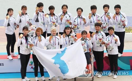 Des membres de l'équipe unifiée de course de bateaux-dragons coréens montent sur le podium lors de la cérémonie de remise des médailles après avoir remporté l'or au 500 mètres féminin aux 18e Jeux asiatiques à Palembang, en Indonésie, le 26 août 2018.