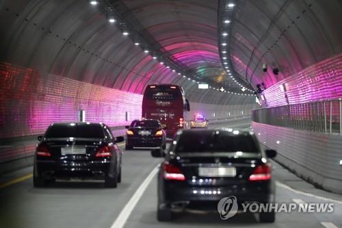 Un bus et des voitures transportant des représentants du gouvernement traversent le tunnel sous-marin de Boryeong, dans le centre de la Corée du Sud, lors d'un essai, le 30 novembre 2021.