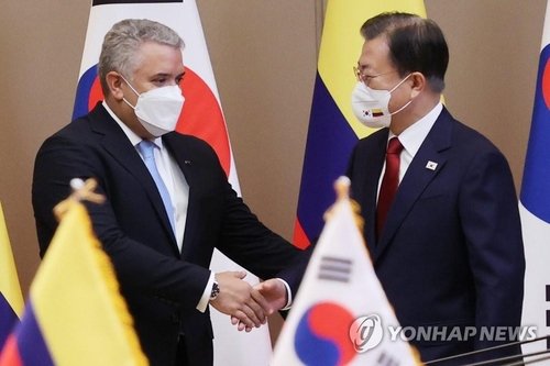 首脳会談前に握手する文大統領（右）とドゥケ大統領＝２５日、ソウル（聯合ニュース）
