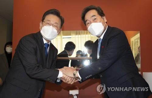 飲食店での会合で握手を交わす李在明氏（左）と李洛淵氏（国会写真記者団）＝２３日、ソウル（聯合ニュース）