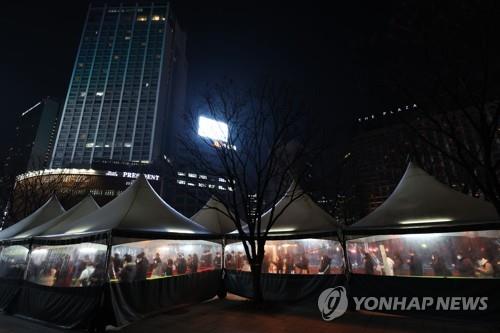 ２７日午後、ソウル市庁前の広場に設置された新型コロナの検査所で順番を待つ人たち＝（聯合ニュース）