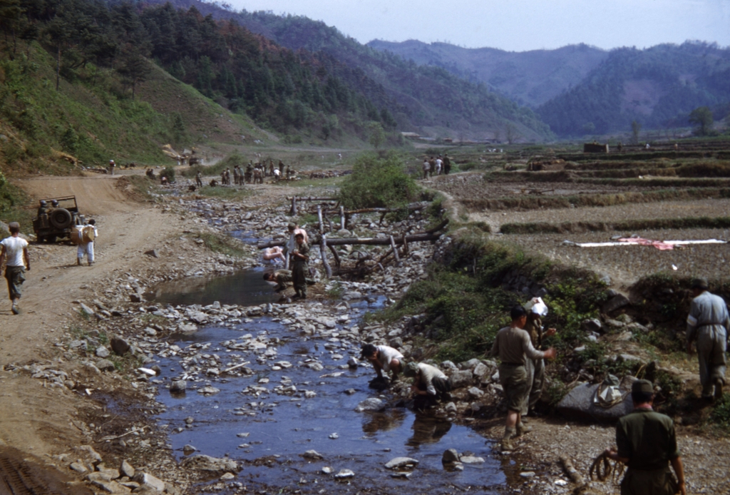 1951년 3월 초 어느 산간마을에서 공사하는 군인들 사이로 지나가는 피란민 행렬