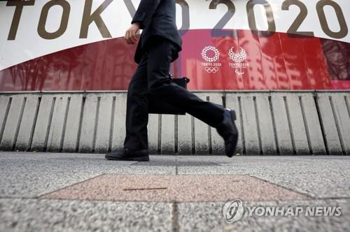 (도쿄 로이터=연합뉴스) 18일 일본 도쿄도에 설치된 올림픽 홍보물 앞으로 양복 차림의 남성이 지나가고 있다.