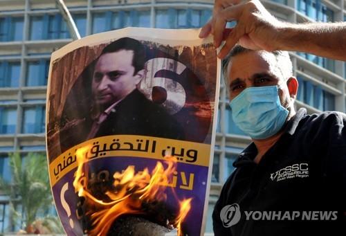 14일(현지시간) 총격 참사 발생 직전 베이루트 대폭발 참사 조사를 주도하는 판사의 얼굴 사진을 불태우며 시위하는 헤즈볼라 지지자들. [UPI 연합뉴스 자료사진. 재판매 및 DB 금지]