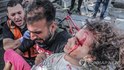 지난 5월 16일(현지시간) 팔레스타인 가자시티에서 한 남성이 이스라엘군의 폭격으로 무너진 건물 더미에서 구해낸 딸을 안아서 옮기고 있다. ［연합뉴스 자료사진. 재판매 및 DB 금지］