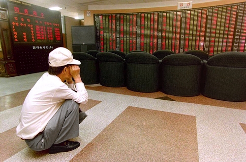 증권사 객장에 쪼그려 앉아 시세판을 보는 투자자. 1997년 IMF 사태는 많은 개미투자자를 울렸다. 1998년 [연합뉴스 자료사진]