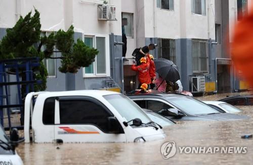 Los bomberos rescatan a los residentes de un apartamento en Daejeon, en el centro de Corea del Sur, varados por las fuertes lluvias y las subsecuentes inundaciones, el 30 de julio de 2020.
