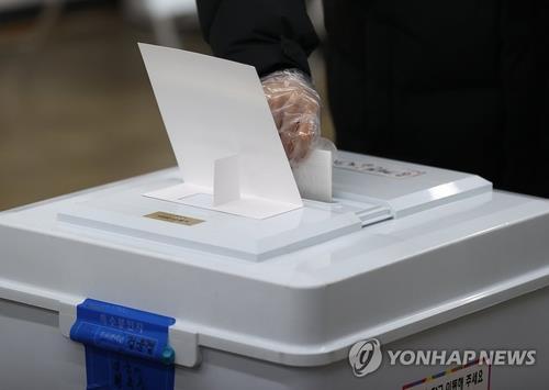 Un votante, que lleva puestos guantes sanitarios, emite su voto, el 7 de abril de 2021, en un colegio electoral, en Seúl, para las elecciones parciales a la alcaldía de la capital.
