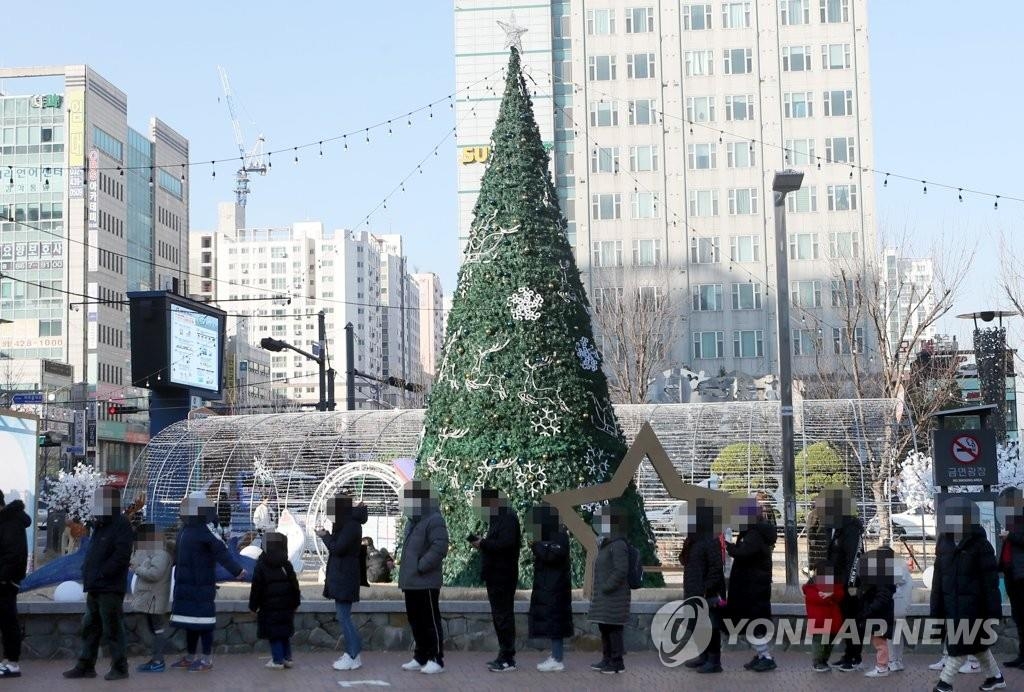 Los ciudadanos esperan en fila frente a un árbol de Navidad para ser examinados del nuevo coronavirus, el 6 de diciembre de 2021, en una clínica provisional en Incheon, a 40 kilómetros al oeste de Seúl, donde se reportaron, la semana pasada, los primeros casos de la variante ómicron en el país. 