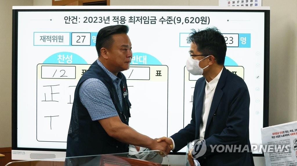 En la foto de archivo, Park Joon-shik (dcha.), jefe del Comité del Salario Mínimo, estrecha la mano de Lee Dong-ho, secretario general de la Federación de Sindicatos de Corea del Sur, en el complejo gubernamental de Sejong, en el centro del país, el 29 de junio de 2022, luego de su participación en la octava sesión plenaria del comité.