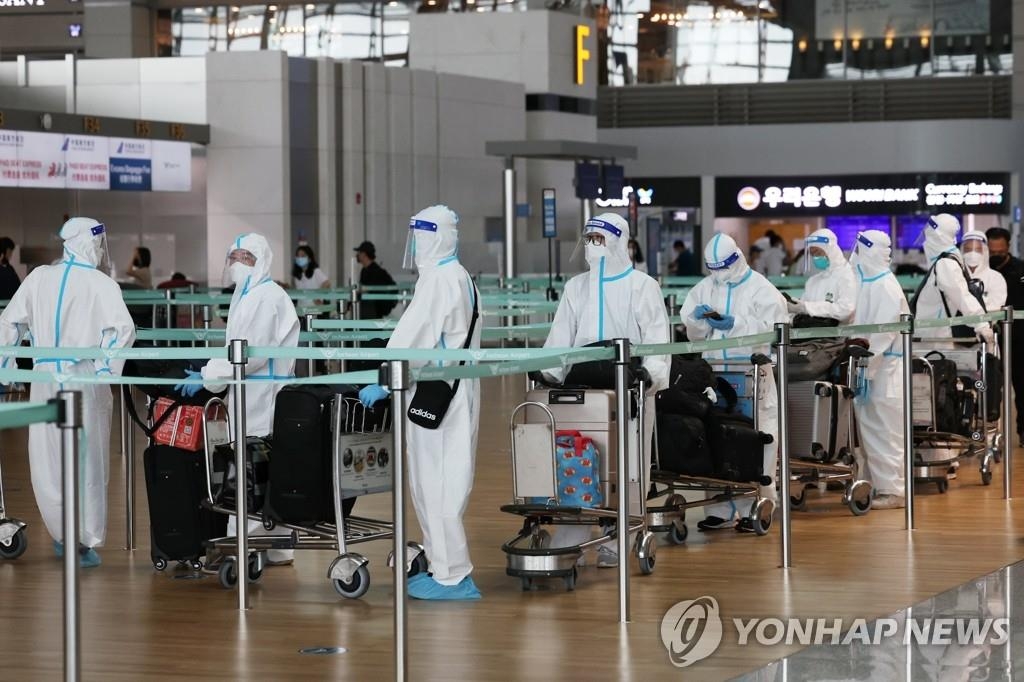 Unos viajeros vestidos con trajes protectores esperan para facturar, el 11 de agosto de 2022, en el Aeropuerto Internacional de Incheon, al oeste de Seúl. 