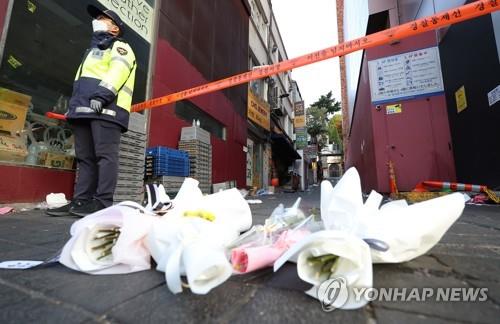 En la imagen se muestran ramos de flores que yacen, el 31 de octubre de 2022, frente a un cordón policial que rodea el sitio en el que ocurrió la avalancha humana, el 29 de octubre, en el barrio de Itaewon, en Seúl.