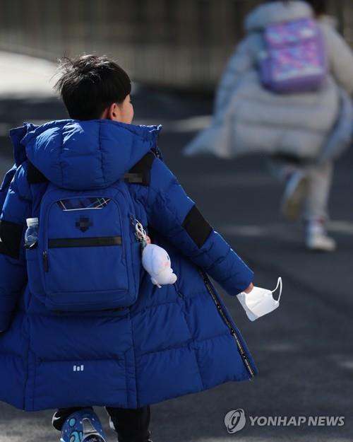 La foto, tomada, el 25 de enero de 2023, muestra a un estudiante de primaria en la ciudad sudoriental surcoreana de Busan, regresando a casa de la escuela con una mascarilla en la mano. El Gobierno planea levantar, el 30 de enero, el mandato del uso de mascarillas en la mayoría de los espacios públicos cerrados, incluidas las escuelas. 