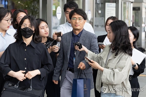 Un oficial de policía (centro, al frente) es rodeado por los reporteros, luego de salir de un interrogatorio, en un hospital de Seúl, el 4 de julio de 2024, al conductor de un accidente mortal, ocurrido, el lunes, en el centro de Seúl, que se cobró la vida de nueve personas.