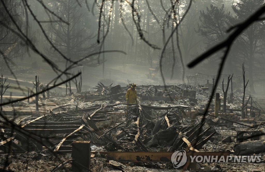 한 소방관이 16일(현지시간) 산불로 소실된 미국 캘리포니아주 파라다이스 지역에서 수색 작업을 하고 있다. [AP=연합뉴스] 