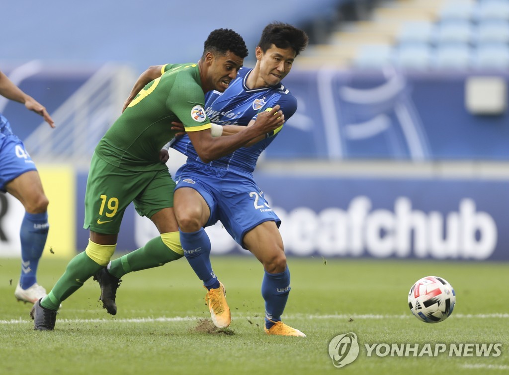 In this Associated Press photo, Kim Tae-hwan of Ulsan Hyundai FC (R) and Alan Carvalho of Beijing Guoan battle for the ball during the teams' quarterfinals match at the Asian Football Confederation Champions League at Al Janoub Stadium in Al Wakrah, Qatar, on Dec. 10, 2020. (Yonhap)