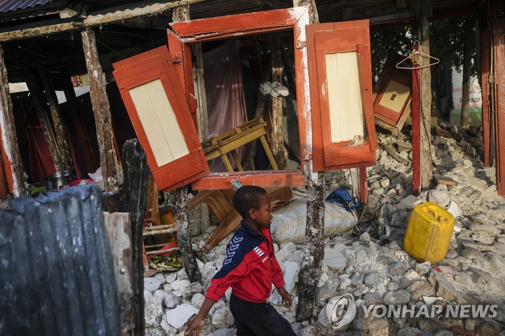 24일(현지시간) 지진으로 무너진 자신의 집 앞을 지나는 아이티 마니셰 소년